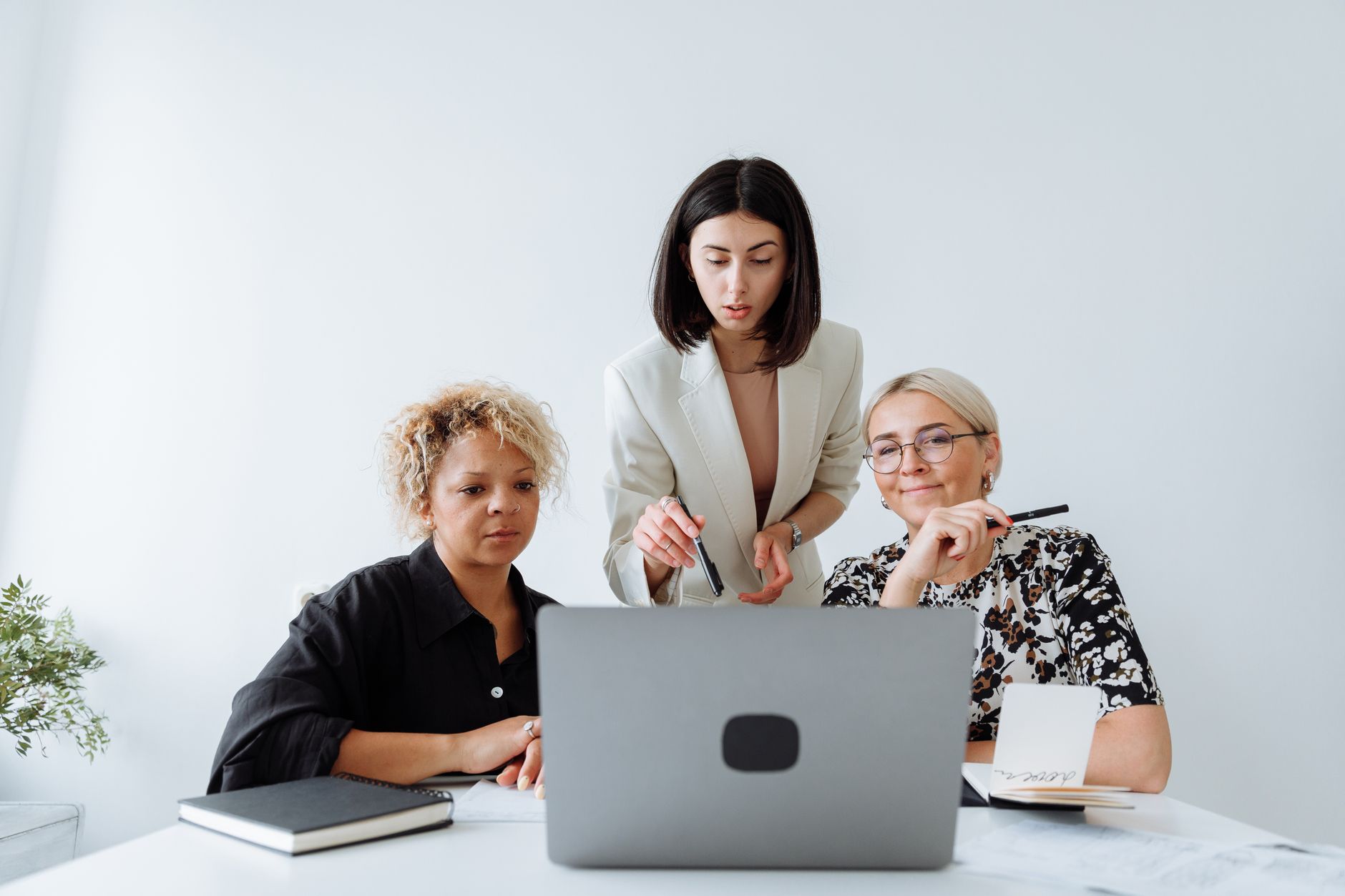 Três pessoas da equipe comercial analisam juntas a tela de um notebook