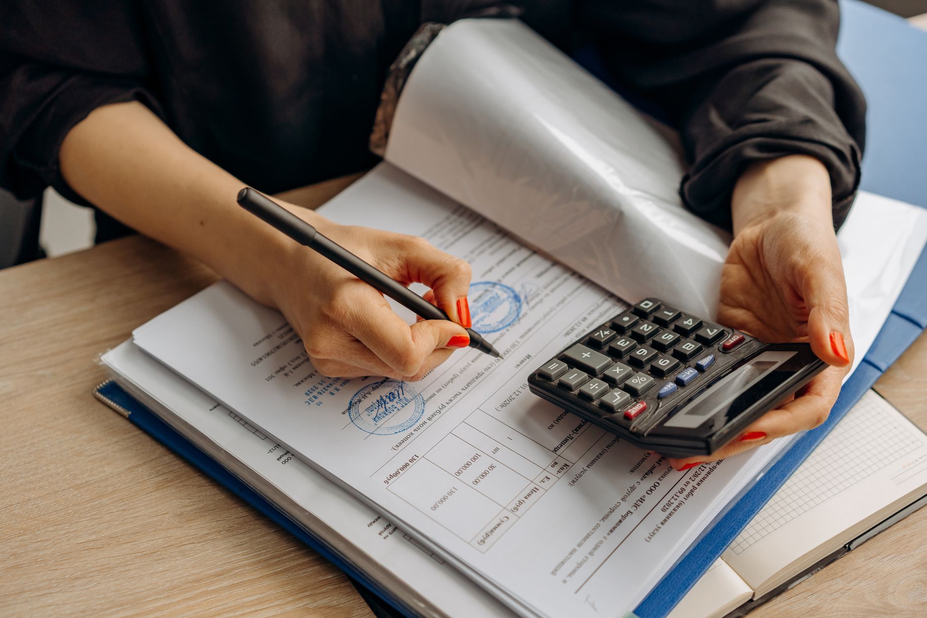 Contador revisando documentos fiscais com calculadora sobre a mesa
