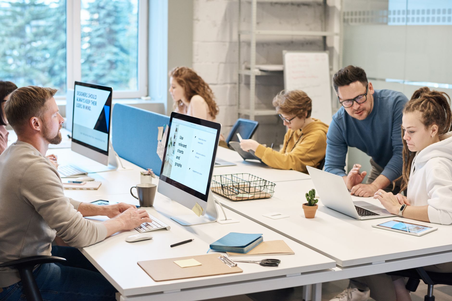 Equipe dando boas-vindas a novo colega em frente ao computador